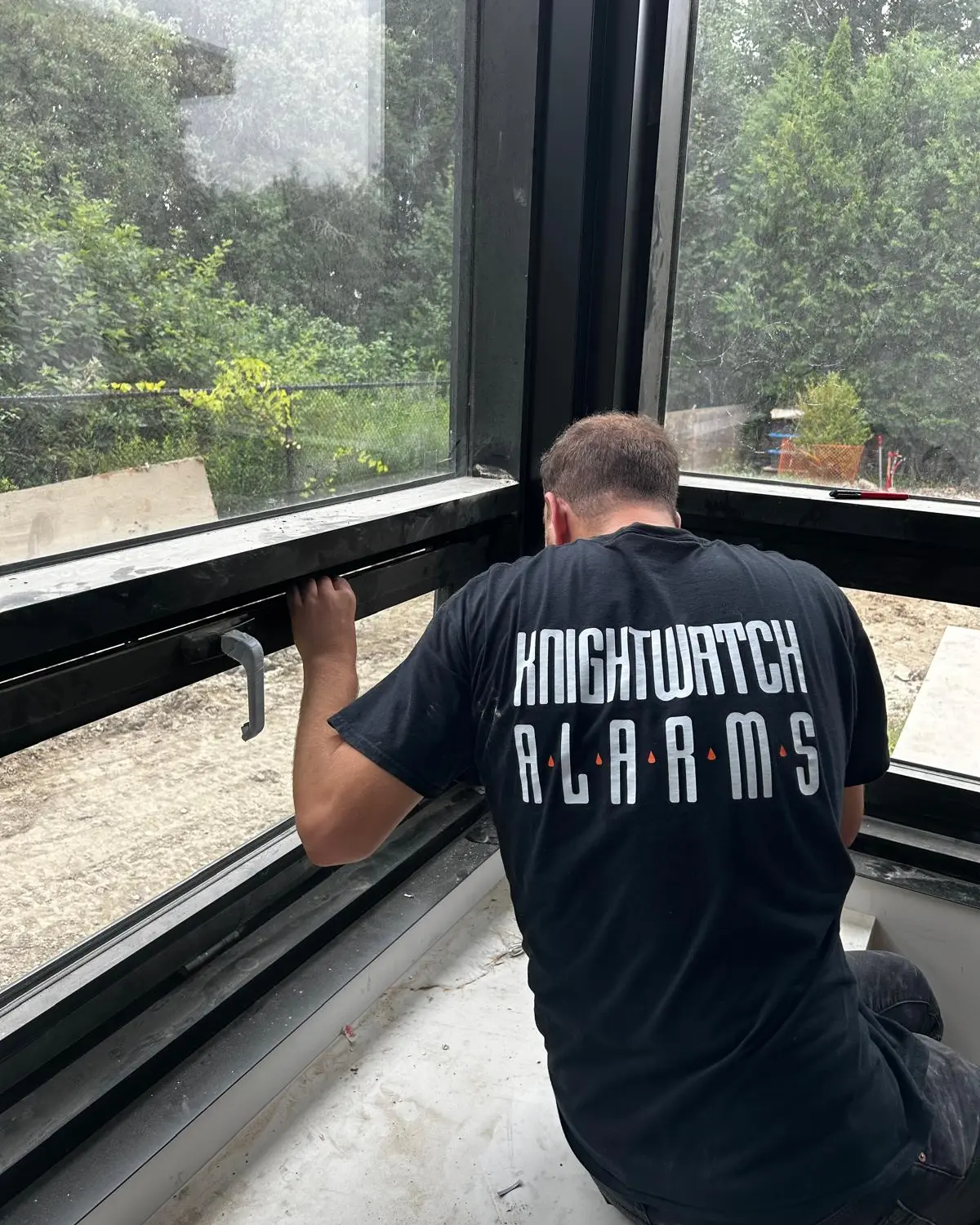 Knightwatch Alarms technician installing a window sensor in a new home